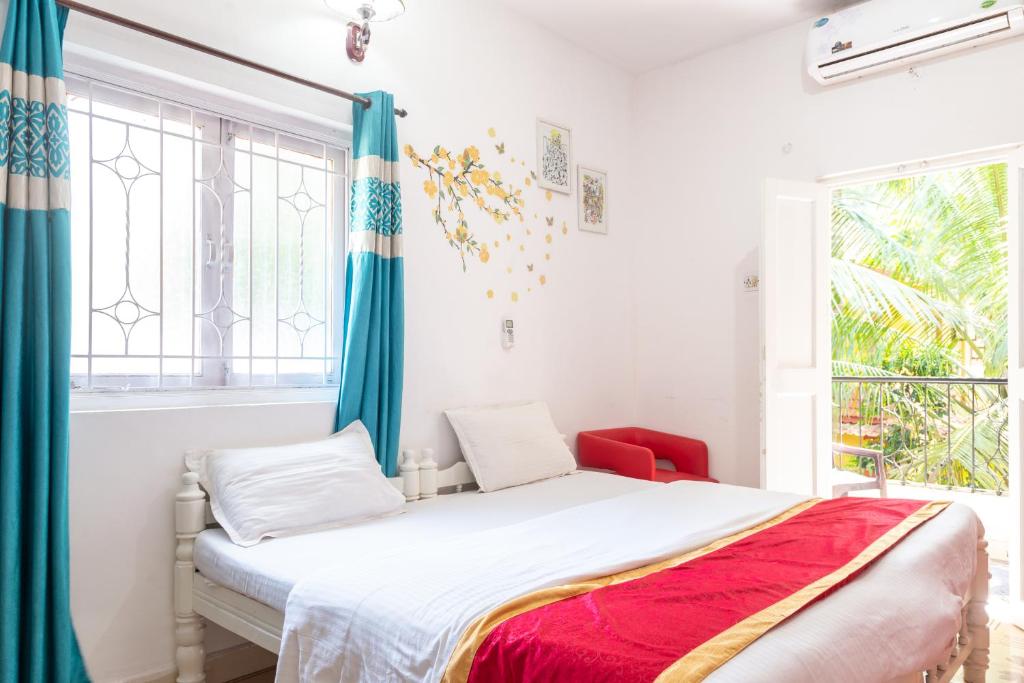 a bedroom with a bed with blue curtains and a window at Oceanic Pearl Beach Guest House in Calangute