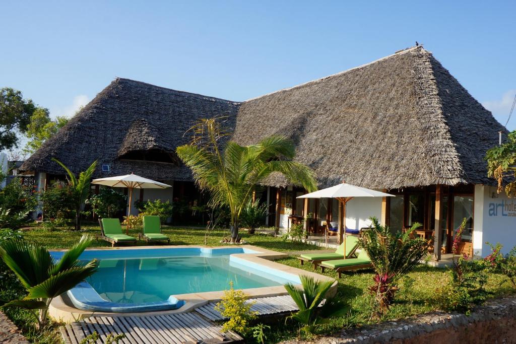 una casa con piscina frente a ella en Art Hotel Zanzibar en Jambiani