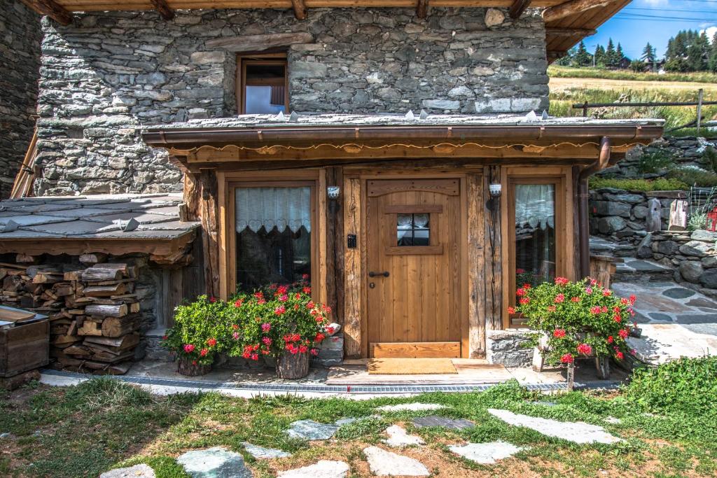 a stone house with a wooden door and flowers at B&B LA VILLE CHAMOIS in Chamois