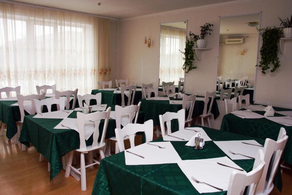 Kyiv Hotel في بولتافا: غرفة بها طاولات وكراسي خضراء وبيضاء