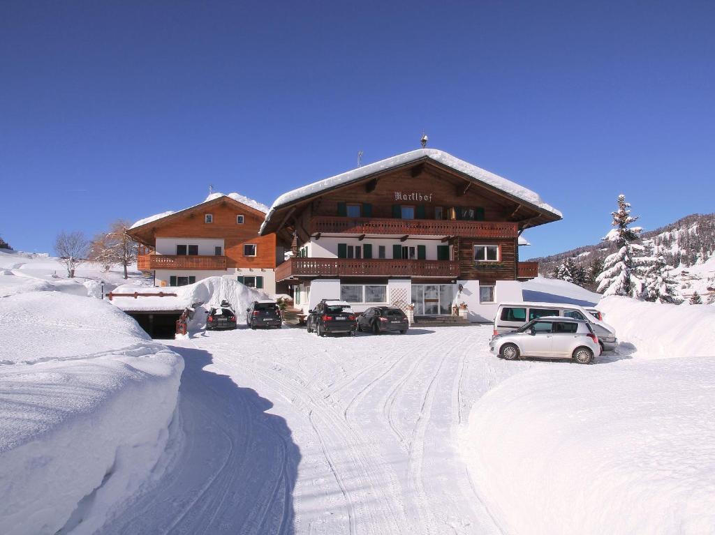 un grande edificio con auto parcheggiate nella neve di Garni Martlhof a Selva di Val Gardena