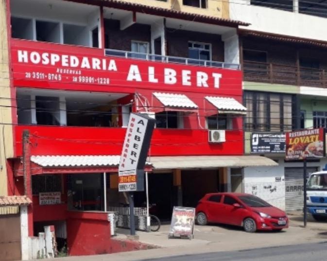 um edifício vermelho com um carro vermelho estacionado em frente dele em Hotel Hospedaria Albert em Cachoeiro de Itapemirim