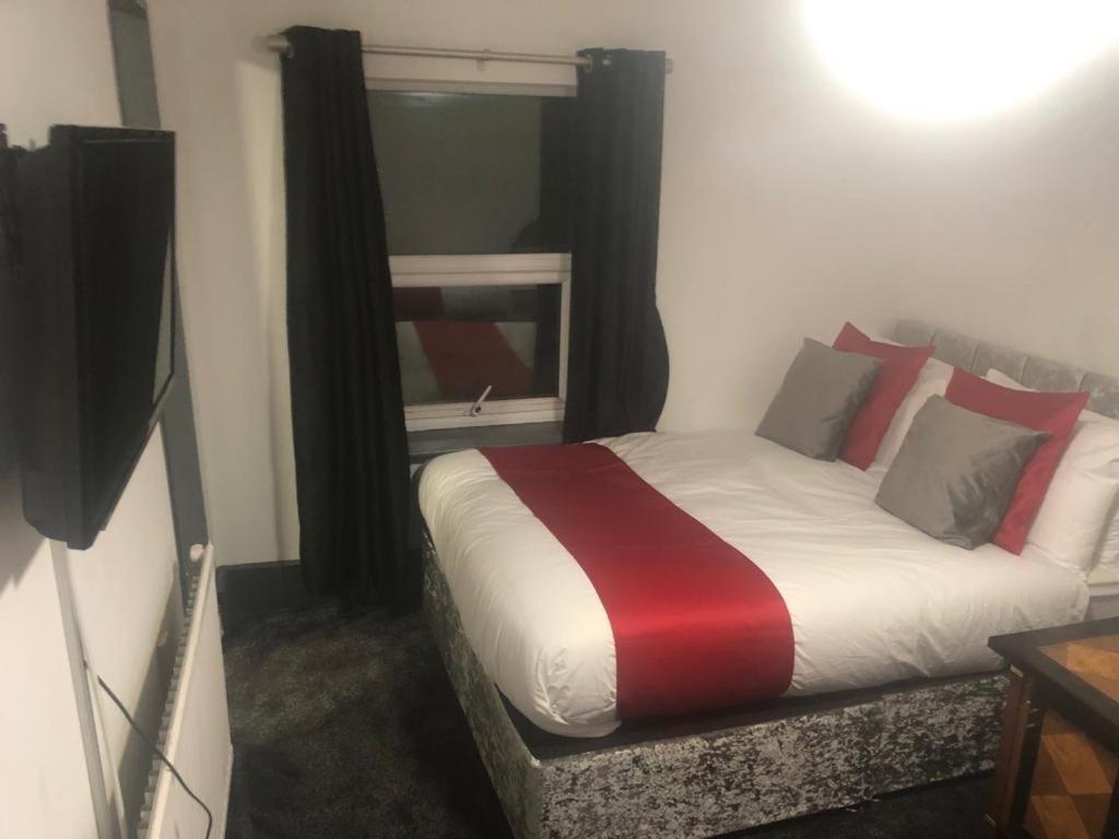 a bedroom with a bed with red and white pillows at Kirubash Central Pier Hotel in Blackpool