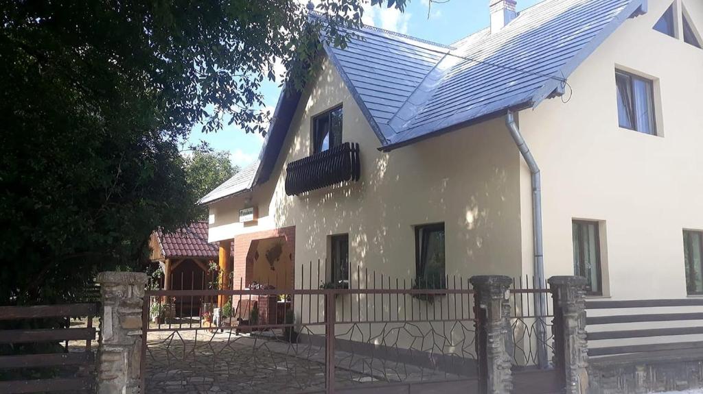 ein weißes Haus mit einem blauen Dach und einem Zaun in der Unterkunft Pensiunea Casa Domniței Sucevița in Suceviţa