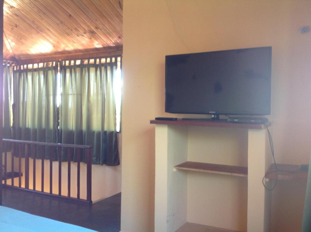 - une télévision sur un support dans une chambre avec une fenêtre dans l'établissement Pousada Por do Sol, à Sao Jorge