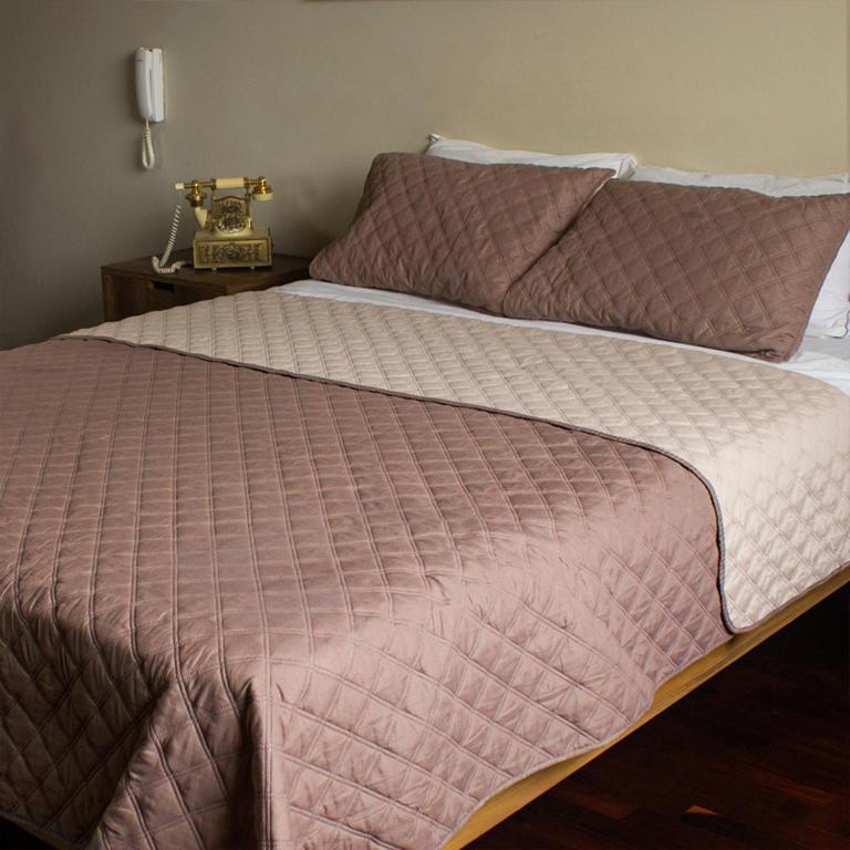 un letto con piumone rosa e telefono di Montreal Hostal a Lima