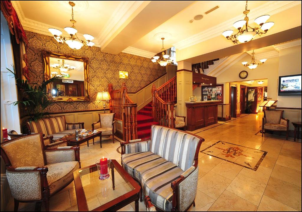een lobby met stoelen en tafels en een trap bij Westenra Arms Hotel in Monaghan