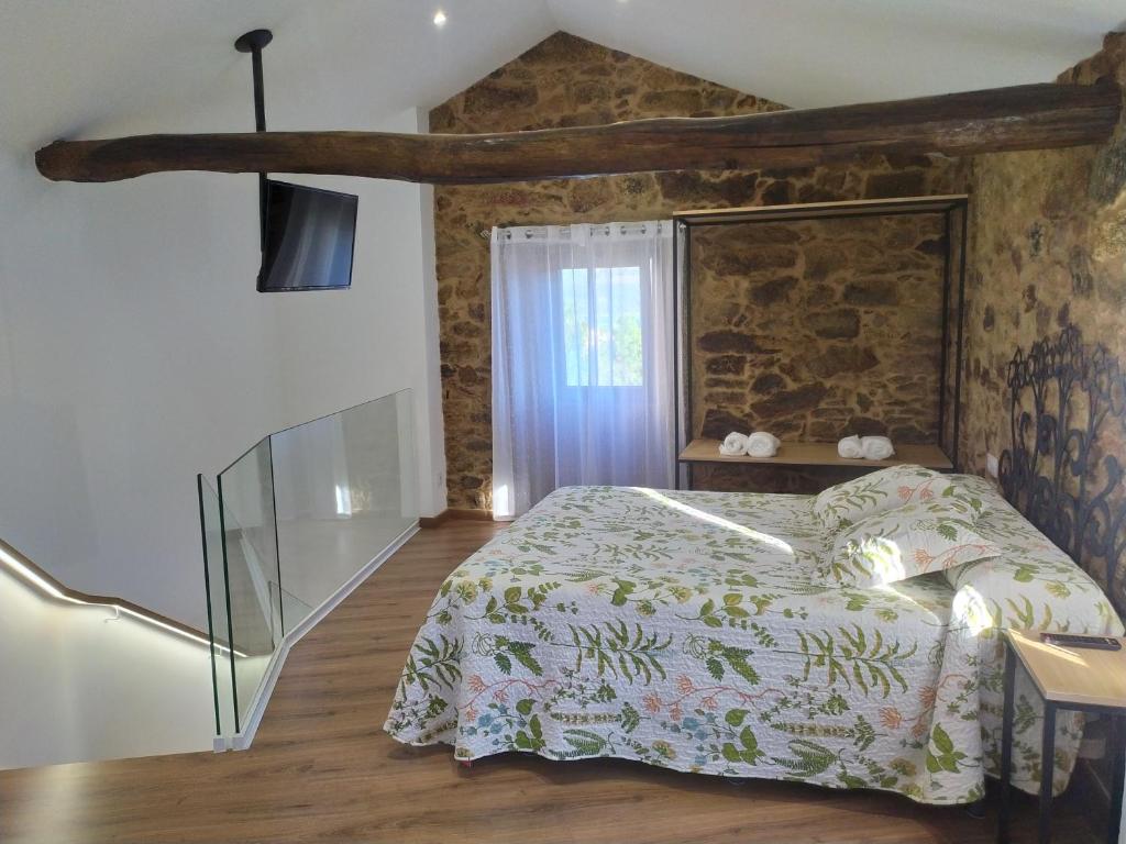 a bedroom with a bed and a stone wall at A xanela in Outes