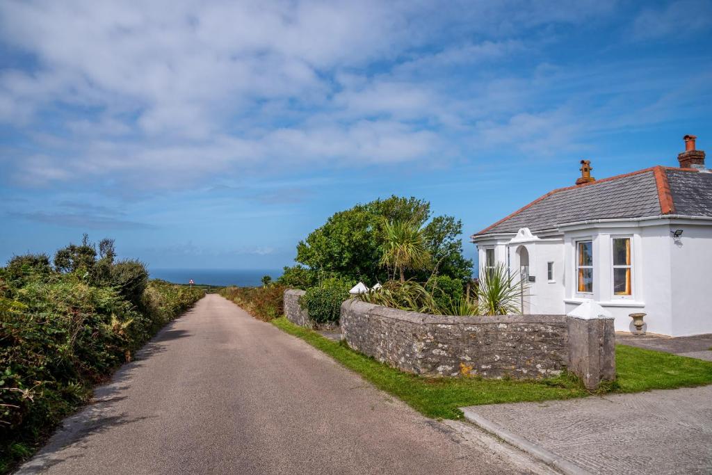 a road leading to a white house with a stone wall at Finest Retreats - Western Watch - Sea Views, Pets Accepted, Sleeps 6 in Lower Boscaswell
