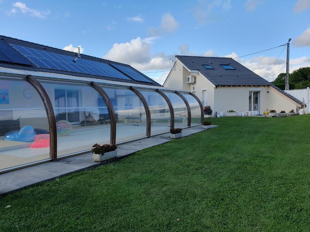ein Glashaus mit Sonnenkollektoren auf einem Hof in der Unterkunft gîte m et m in Nébouzat
