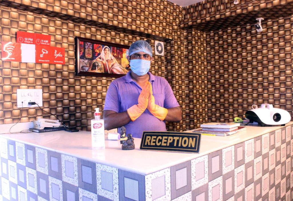 een persoon achter een toonbank met een masker bij Hotel Galaxy Inn in Durgapur