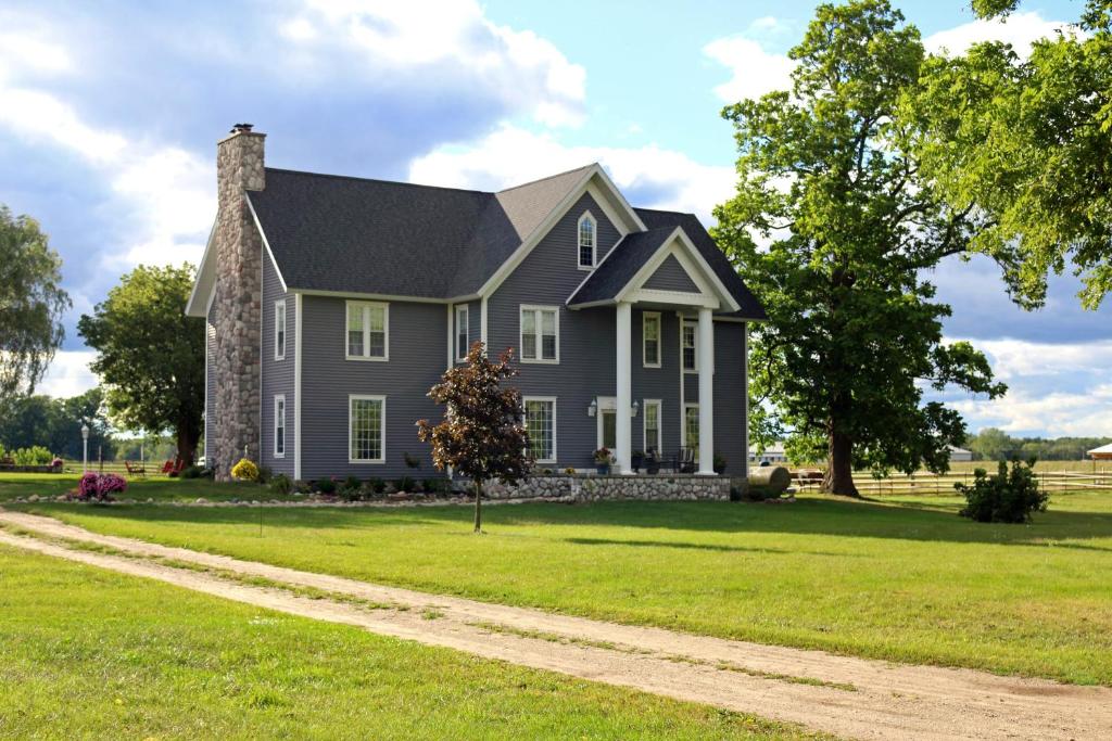 a gray house on a green lawn with a dirt road at LOJ BNB in Morley