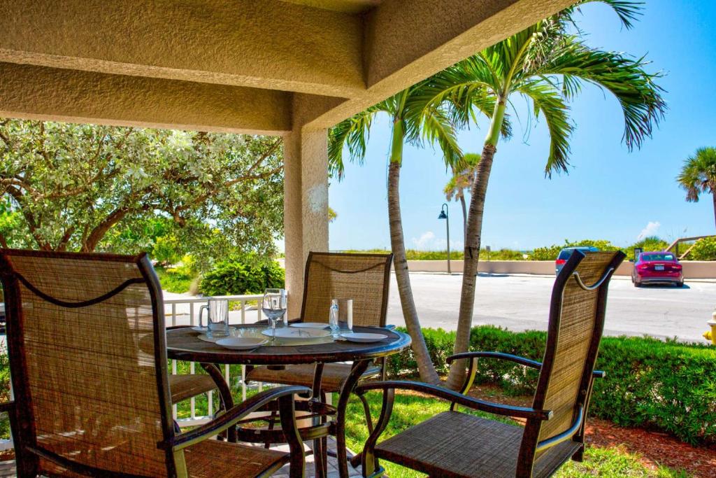 a table and chairs on a patio with palm trees at 1 - Beach Club At Pass-A-Grille in St Pete Beach