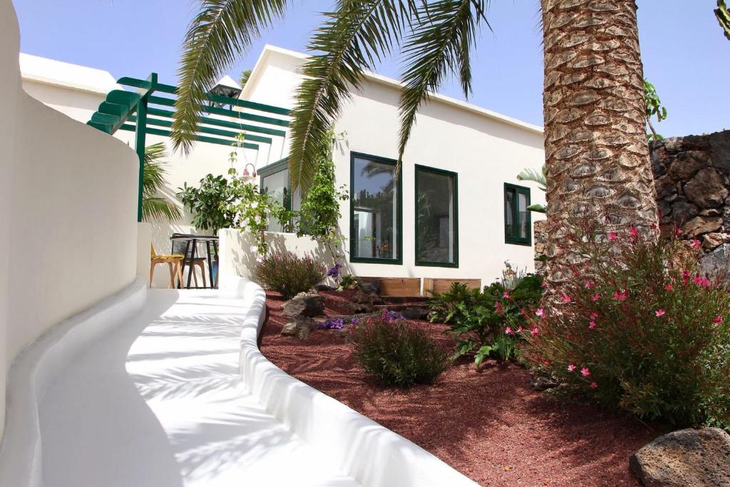 une maison blanche avec un palmier dans la cour dans l'établissement Unique, Stylish & Calm El Estanque by the Sea, Adults Only, à Costa Teguise
