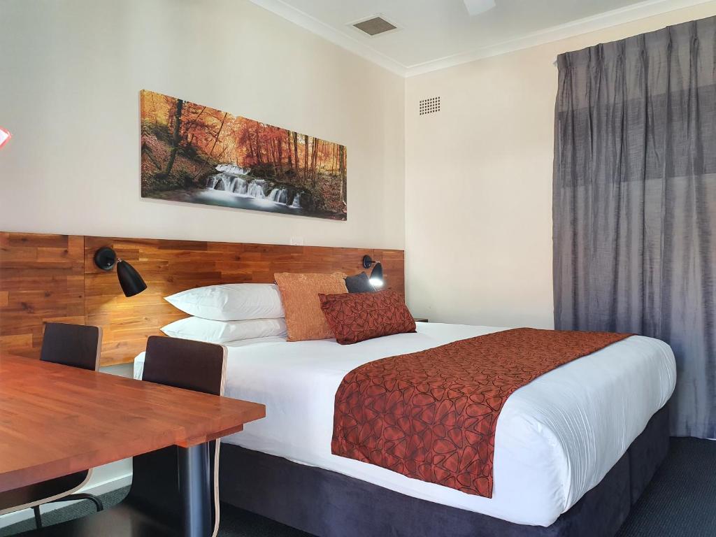 ゴールバーンにあるBlack Sheep Motel Goulburnのベッドとテーブルが備わるホテルルームです。