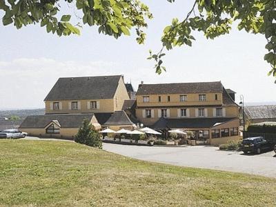 un grand bâtiment avec des voitures garées devant lui dans l'établissement Logis Hôtel de la Tour, à Masseret