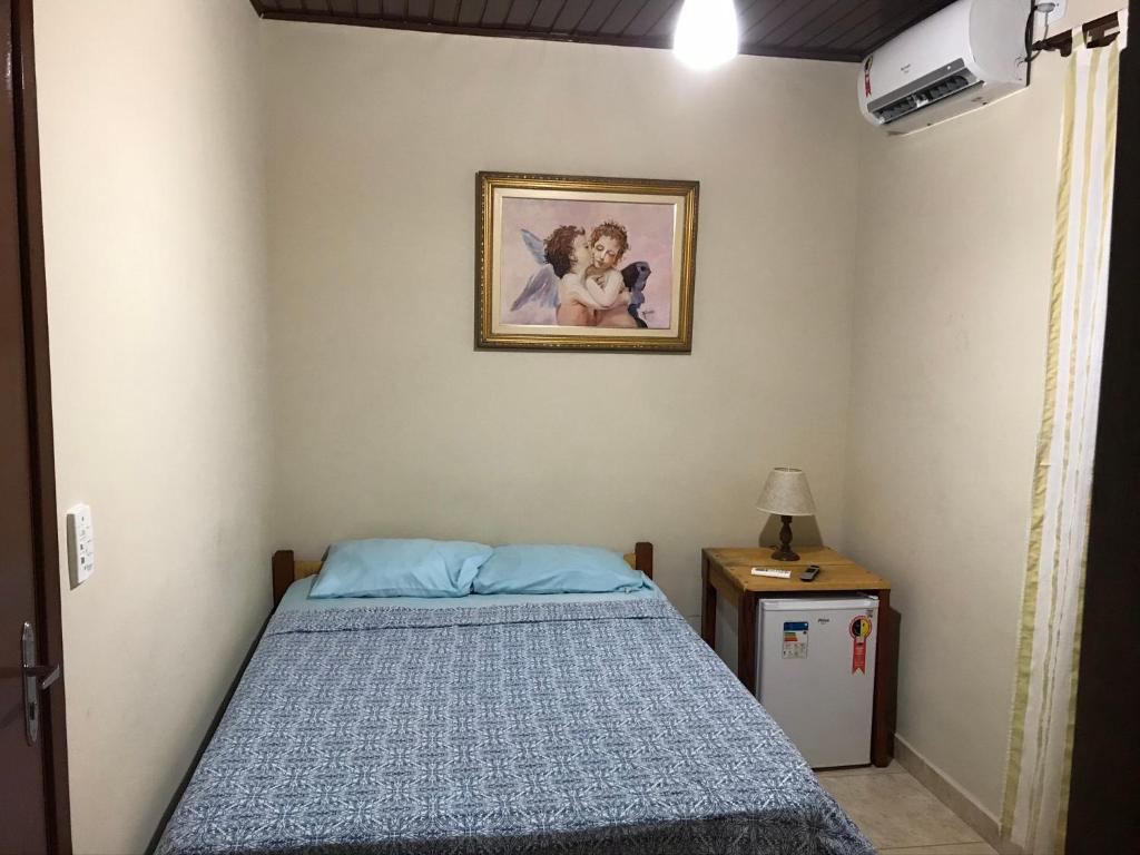 a bedroom with a bed and a picture on the wall at Pousada Jolly Roger in Bertioga