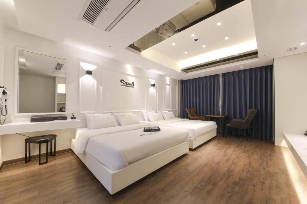 1 dormitorio con 1 cama blanca grande y escritorio en Stay Hotel en Gwangju
