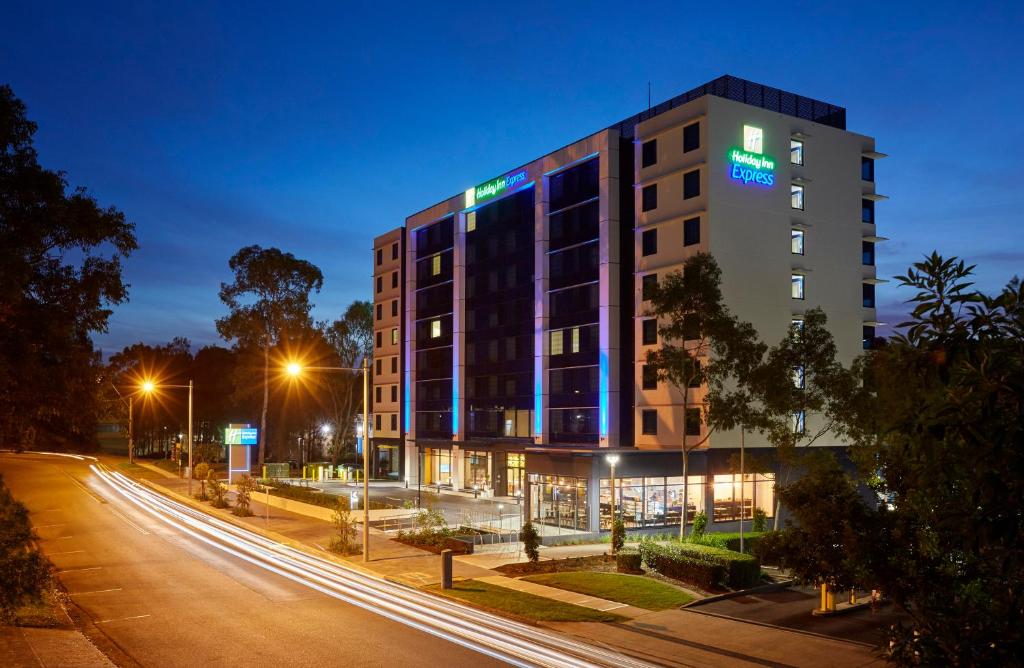 um edifício numa rua à noite com luzes em Holiday Inn Express Sydney Macquarie Park, an IHG Hotel em Sidney