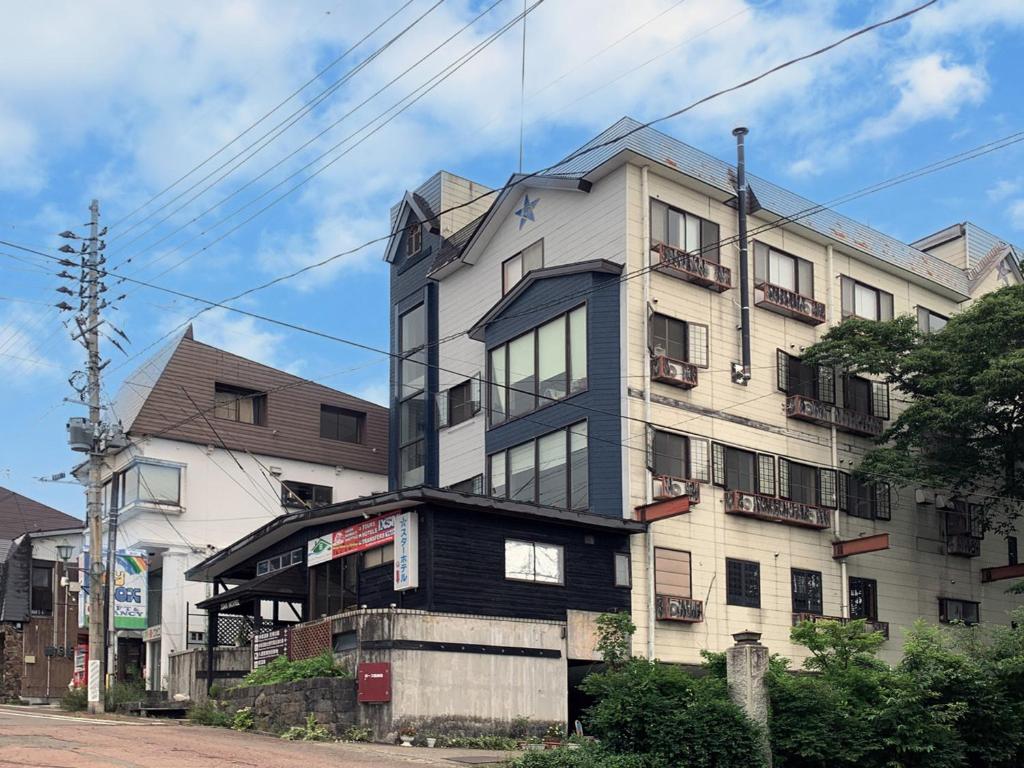 a tall white building with windows on a street at Star Hotel Akakura in Myoko