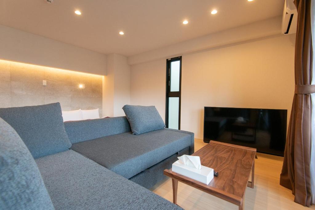 ein Wohnzimmer mit einem blauen Sofa und einem Fernseher in der Unterkunft MK Hotels Nishinakasu in Fukuoka