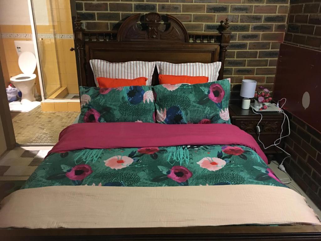 a bed with red and green comforter and pillows at Motel Studio room in Somersby