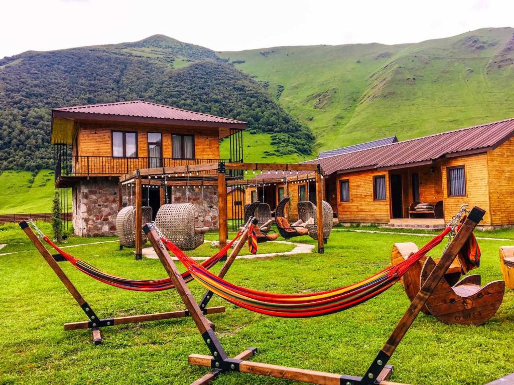 a house with a hammock in front of a house at Hotel Migu Yard in Stepantsminda