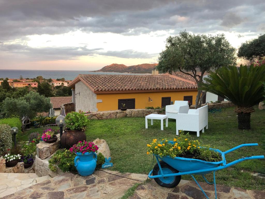 a garden with a wheelbarrow with flowers and a house at Villa Relax in Santa Lucia