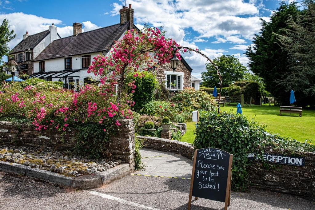 um sinal em frente a uma casa com flores em The Greyhound Inn and Hotel em Usk