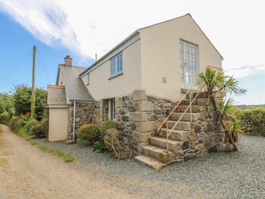a stone house with a stone staircase leading up to it at Higher Roskorwell Cottage in Helston