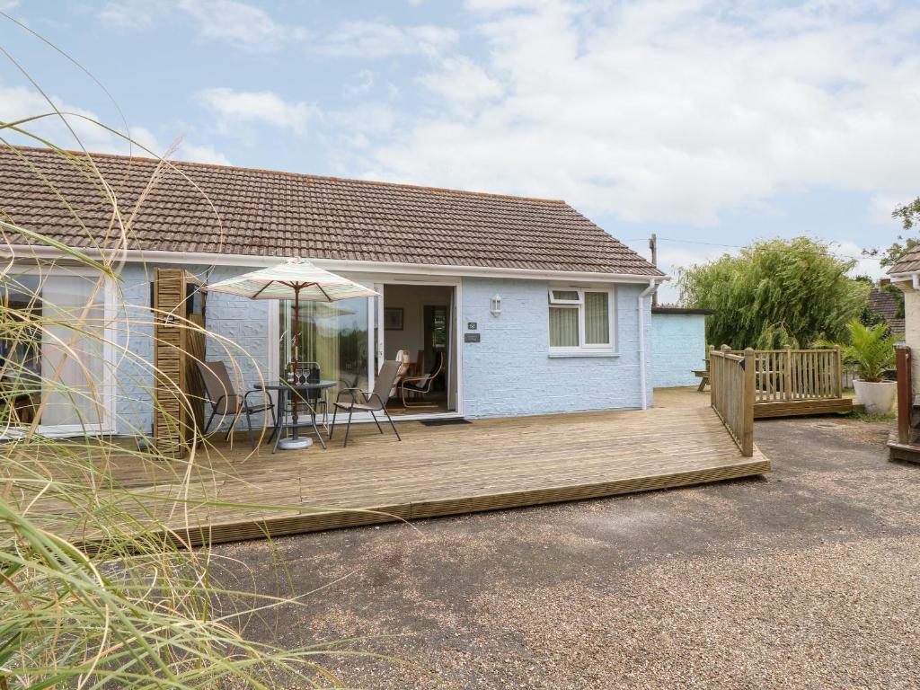 a house with a wooden deck with a table and an umbrella at Buddleia Cottage in Seaview