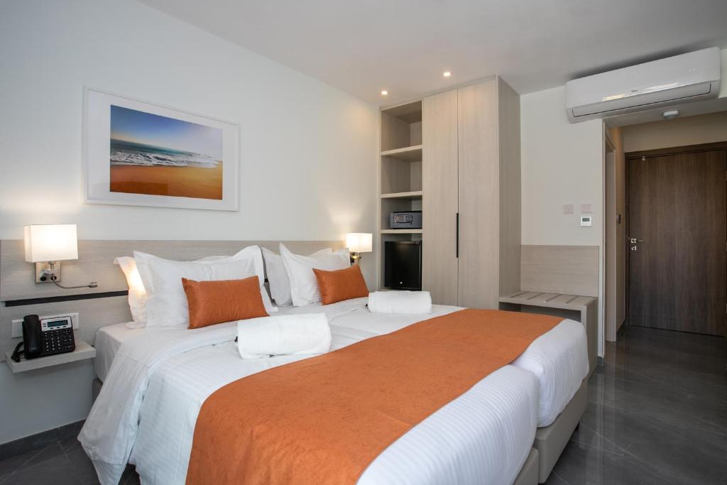 a bedroom with a large bed with an orange blanket at Best Western Plus Larco Hotel in Larnaka