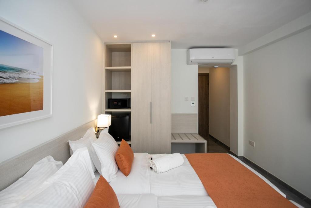 a bedroom with a large white bed with orange pillows at Best Western Plus Larco Hotel in Larnaka