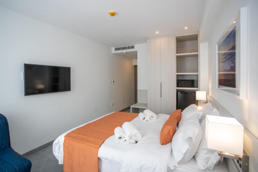 a bedroom with a bed with white sheets and orange pillows at Best Western Plus Larco Hotel in Larnaka