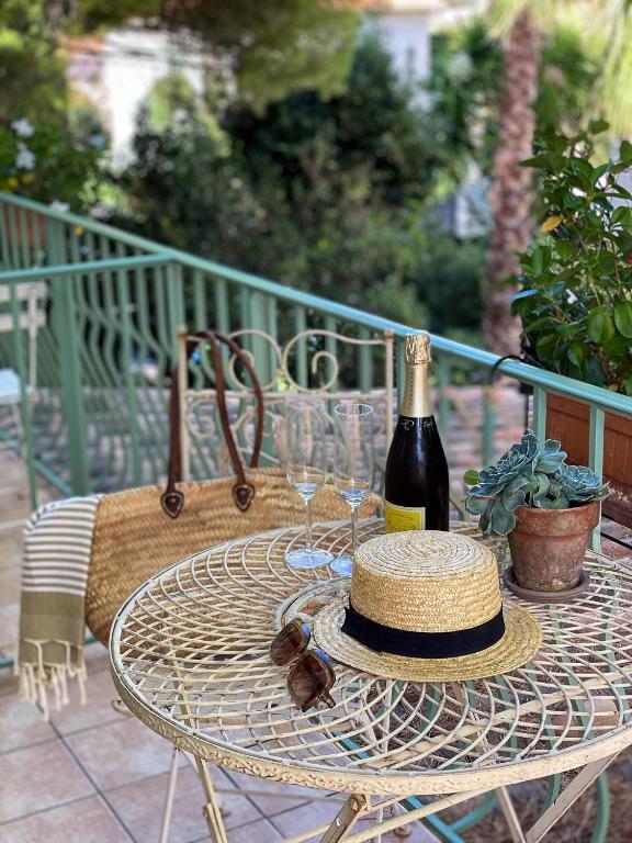 a table with a bottle of wine and a hat on it at Hotel Le Ponteil in Antibes