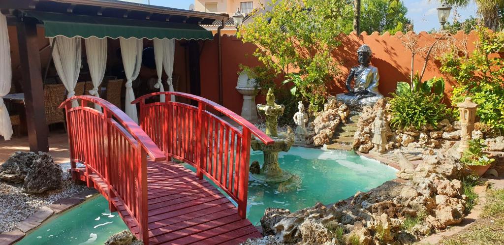 um jardim com uma ponte vermelha sobre um pequeno lago em Hotel Iris La Eliana em La Eliana