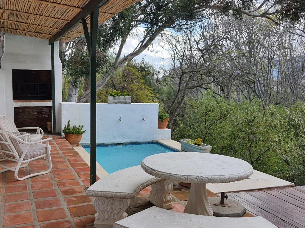 un patio con una mesa y una piscina en Little Willow Brooke, en Franschhoek