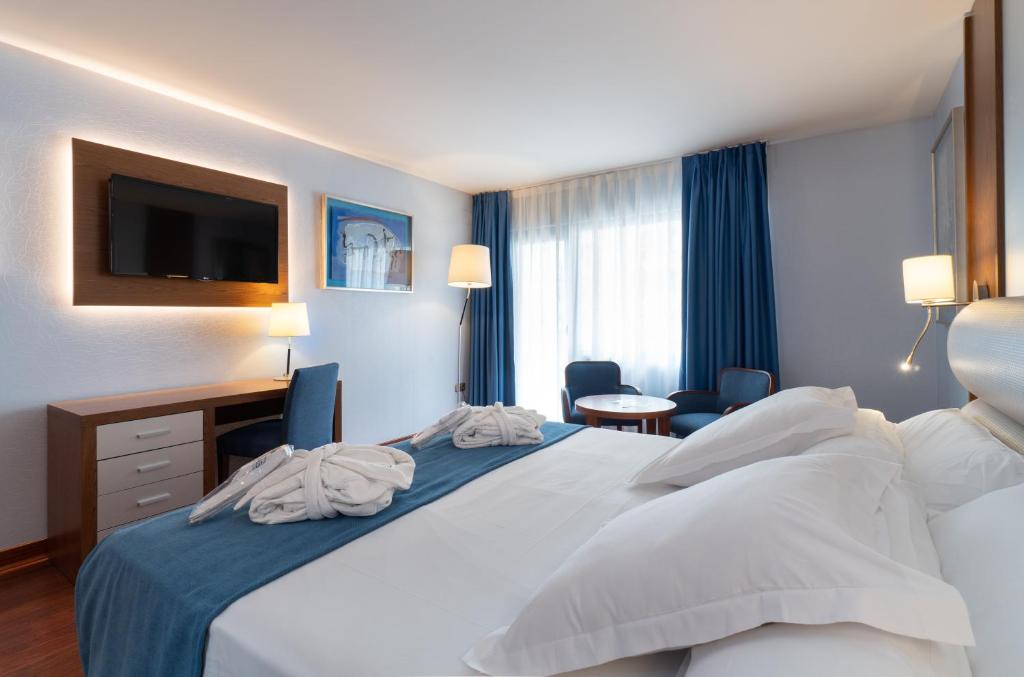 Habitación de hotel con cama, escritorio y TV. en Hotel MS Maestranza Málaga, en Málaga