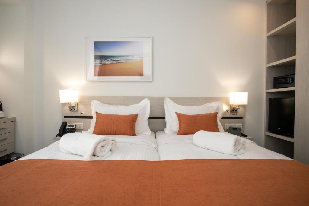 a bedroom with a large bed with orange and white pillows at Best Western Plus Larco Hotel in Larnaka