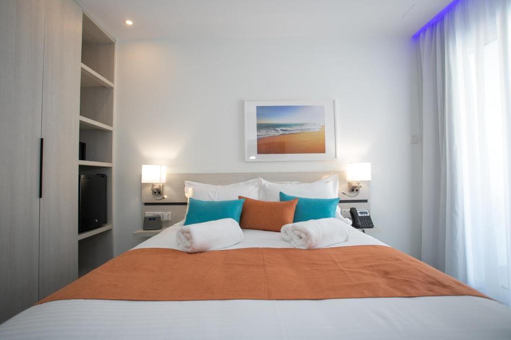 a bedroom with a large bed with blue and orange pillows at Best Western Plus Larco Hotel in Larnaka