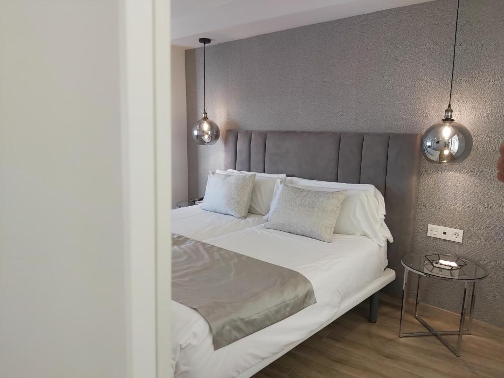sypialnia z dużym łóżkiem z białą pościelą i poduszkami w obiekcie Del Parque Flats Flores Premium w Maladze