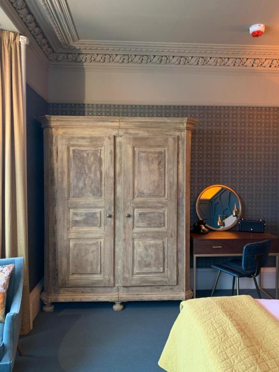a wooden cabinet in a bedroom with a desk at No.26 By The Sea in Oban
