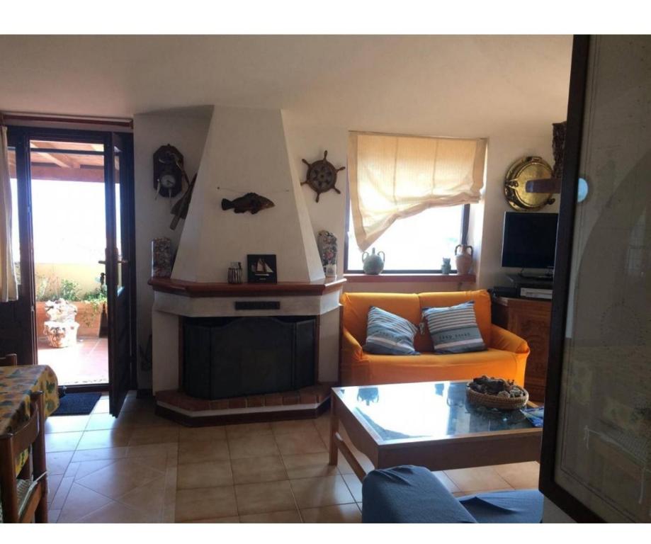 sala de estar con sofá naranja y chimenea en Bella vista, en Cala Gonone