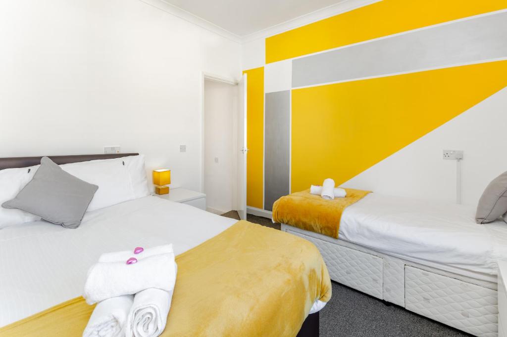- 2 lits dans une chambre de couleur jaune et blanche dans l'établissement Cosy Anfield Guesthouse - FREE parking, à Liverpool