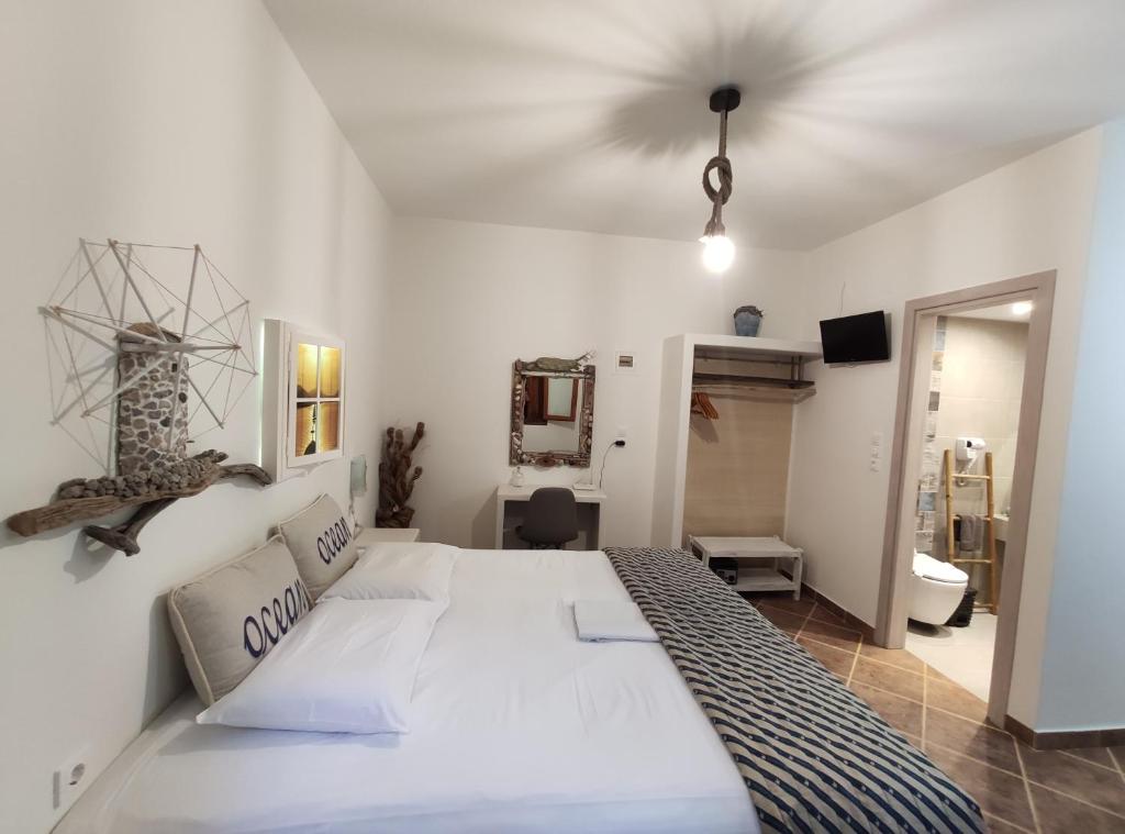 Un dormitorio con una gran cama blanca y un baño. en Medousa, en Adamas