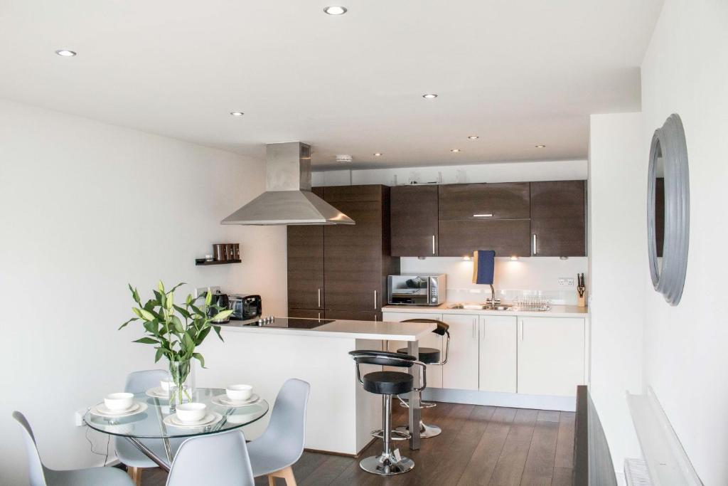 uma cozinha com armários brancos e uma mesa e cadeiras em Contractor Apartment & Private Parking & Central Stevenage em Stevenage