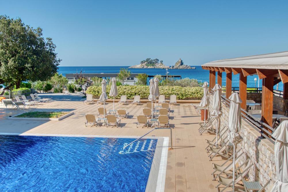 a swimming pool with umbrellas and chairs and a swimming pool at Hotel Palas in Petrovac na Moru