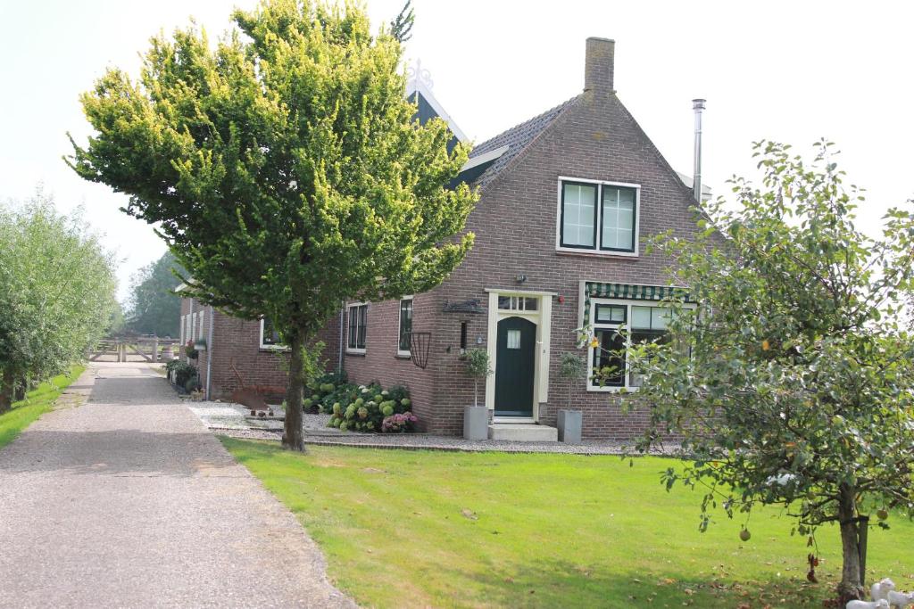 een stenen huis met een boom ervoor bij Bed en Breakfast Het Friesche Paard in Purmer