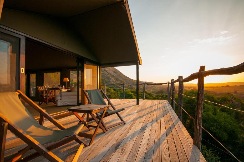 una terraza con 2 sillas y una mesa en una casa en HillsNek Safari Camp – Amakhala Game Reserve, en Reserva de Amakhala
