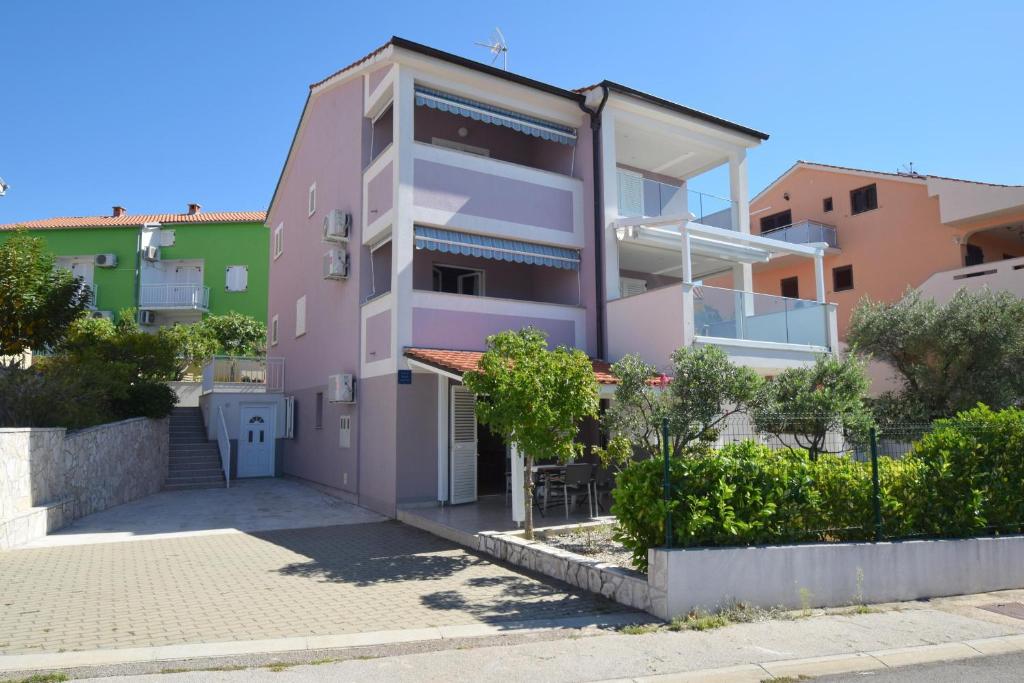 une maison rose avec une cour en face dans l'établissement Apartments Marjolovic, à Njivice